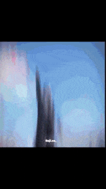 a blurry picture of a person 's hand against a blue sky with the word baji visible