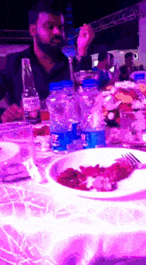 a man sits at a table with a bottle of corona