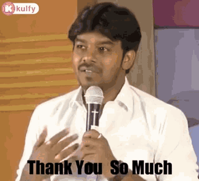 a man is holding a microphone in his hand and saying thank you so much .