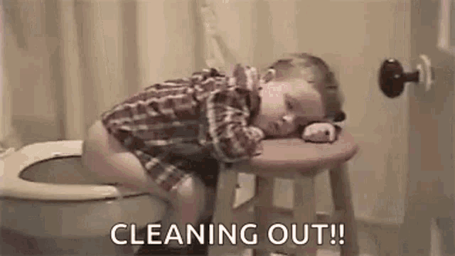 a baby is laying on a stool next to a toilet .