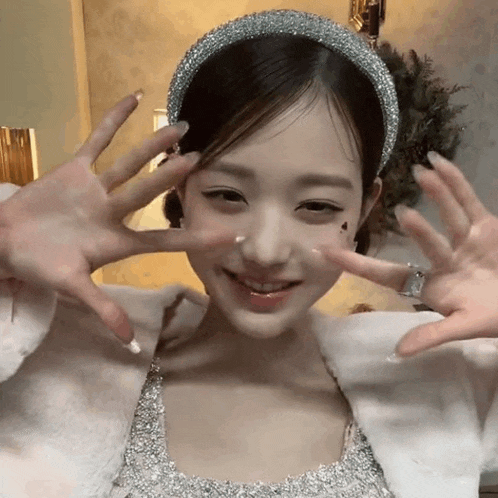 a woman wearing a silver headband is making a peace sign
