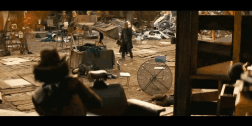 a man in a cowboy hat stands in a messy area