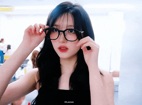 a woman wearing glasses and a black tank top with ive autumn written on the bottom