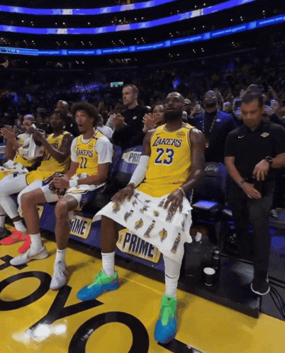 a man in a lakers jersey sits in the stands
