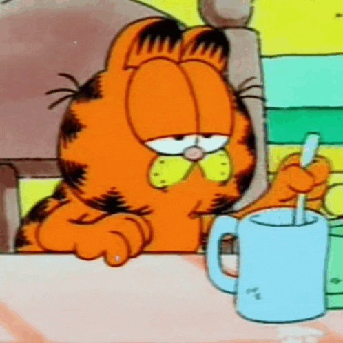 garfield is sitting at a table with a cup and spoon