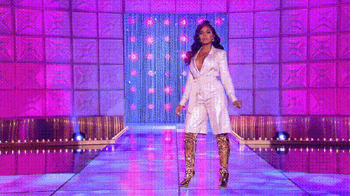 a woman is walking down a runway wearing a suit and boots .