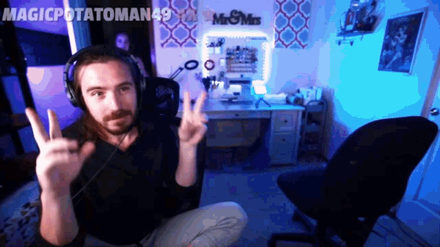 a man wearing headphones is giving a peace sign in front of a mr & mrs sign on the wall