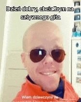 a bald man wearing sunglasses is smiling .