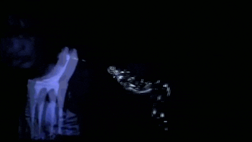 a blurry image of a person in a dark room with a skull in the background