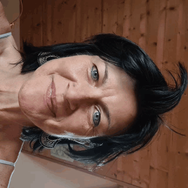a woman with black hair and blue eyes looks down at the camera