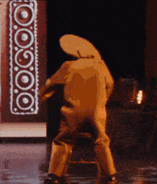 a man in a cowboy hat is dancing on a stage in front of a sign that says ' oooo '