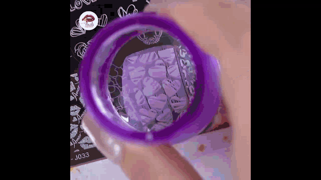 a close up of a person holding a purple cup with a stamp on it