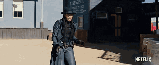 a woman in a cowboy outfit is standing in front of a building that says t. nessett very office