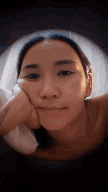 a close up of a woman laying down with her hand on her face