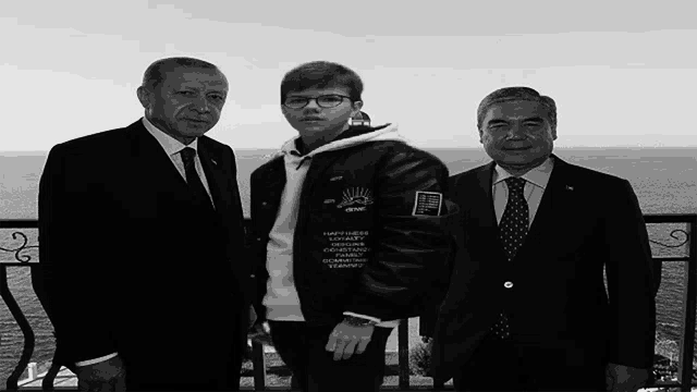 a boy wearing a jacket that says happiness on it poses for a picture with two men