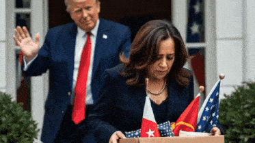 a man in a suit and tie stands behind a woman holding a box with flags in it
