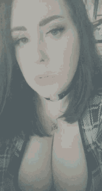 a woman wearing a choker and a plaid shirt is looking at the camera