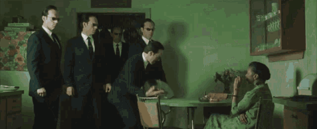 a man in a suit and tie stands in a kitchen looking at the camera