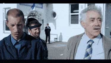 a man wearing a welding helmet talks to two other men