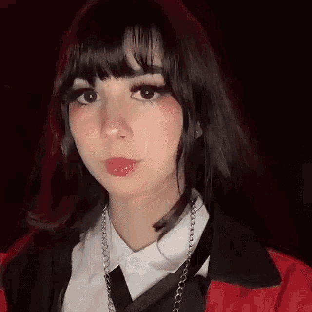 a close up of a woman wearing a red jacket , white shirt , and black tie .