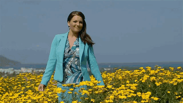 a woman in a blue suit stands in a field of flowers