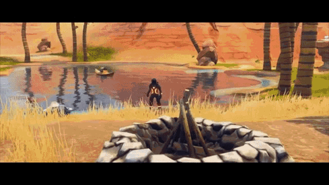 a man is standing next to a fire pit in front of a lake in a video game .