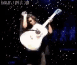 a man is holding a guitar in the air and the website hangups.tumblr.com is visible in the corner