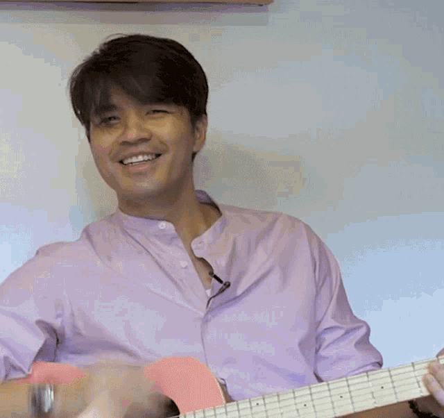 a man in a pink shirt is smiling and covering his face