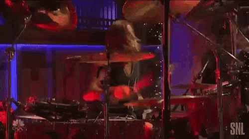 a man is playing drums on a stage in front of a microphone and a drum set .
