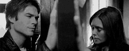 a man and a woman are standing next to each other and looking at each other in a black and white photo .