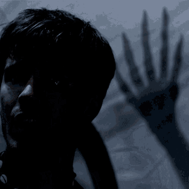 a man 's face is shown in the dark with a blurred background