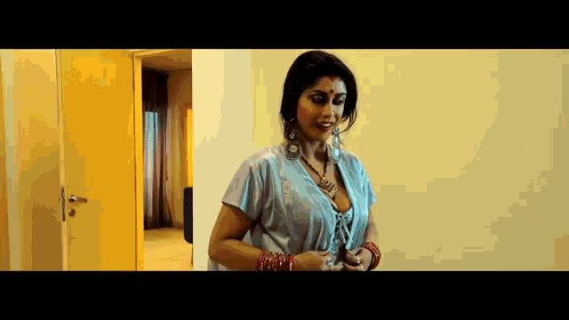 a woman in a blue dress is standing in front of a door in a room .