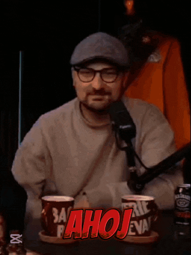 a man sitting in front of a microphone with the word ahoj written on the screen