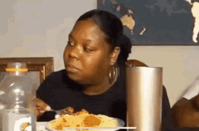 a woman is sitting at a table eating food with a fork and knife .