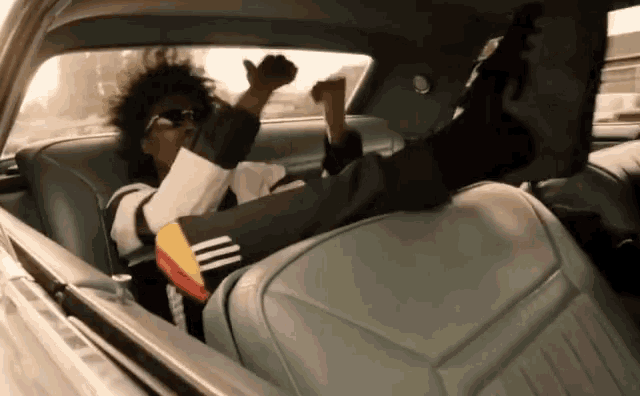 a person is sitting in the back seat of a car with their feet out the window