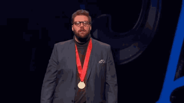 a man in a suit with a medal around his neck stands on a stage and says what a strange thing to say