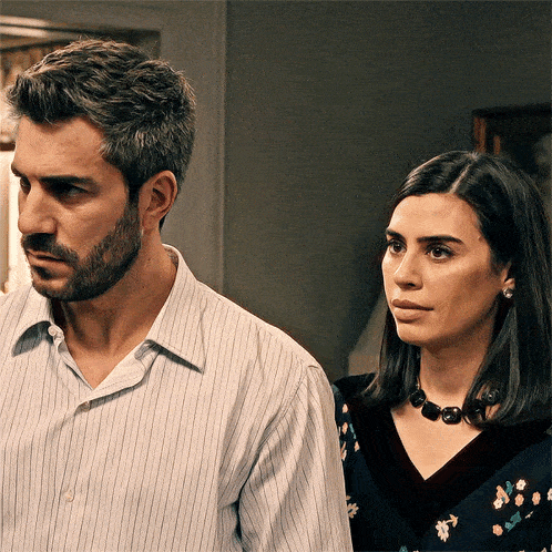 a man and a woman are standing next to each other and looking at something