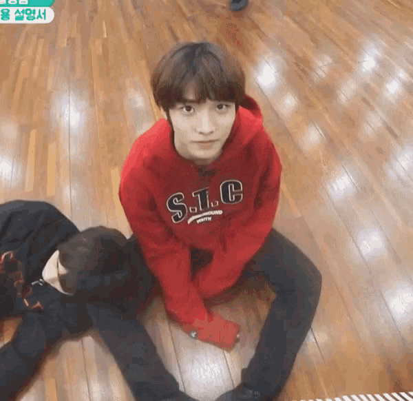 a man in a red s.l.c sweatshirt sits on the floor