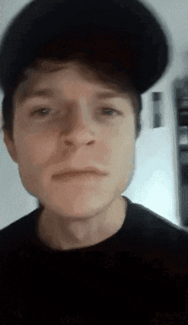 a close up of a man wearing a hat and a black shirt .