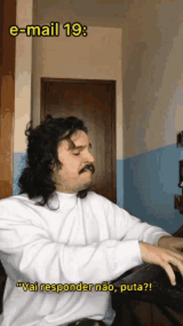 a man with long hair and a mustache is sitting in front of a keyboard and says " vai responder não puta "
