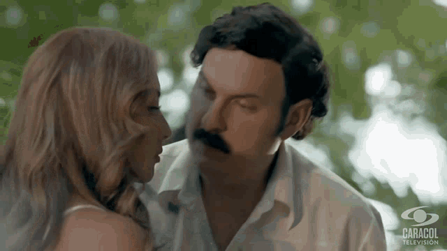 a man and a woman are kissing in front of a caracol television logo
