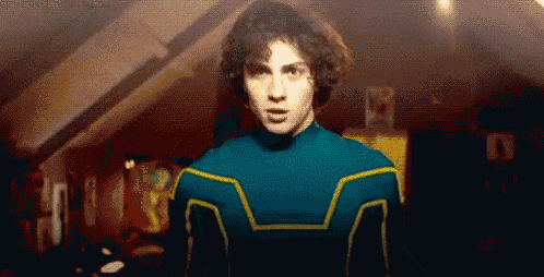a man in a blue and yellow superhero costume is standing in a dark room .