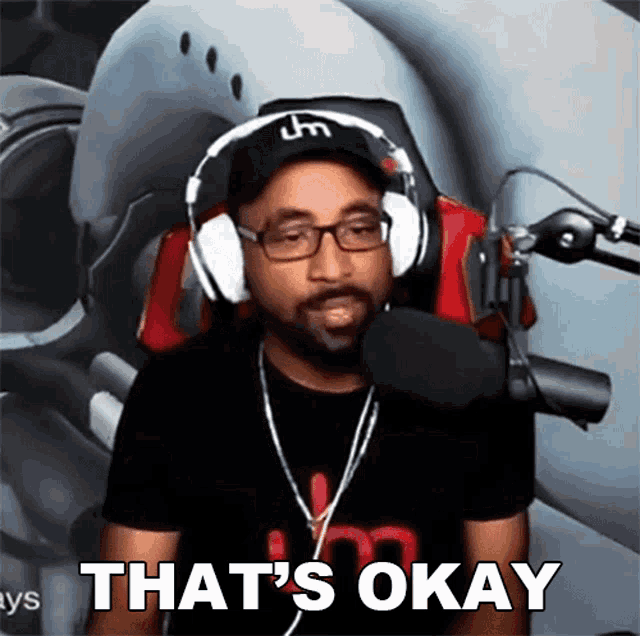 a man wearing headphones and glasses says that 's okay in front of a microphone