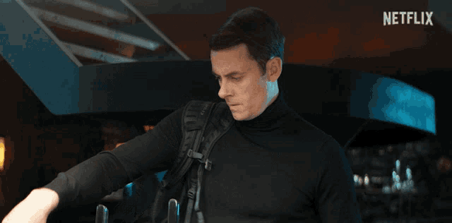 a man in a black turtleneck is standing in front of a sign that says netflix