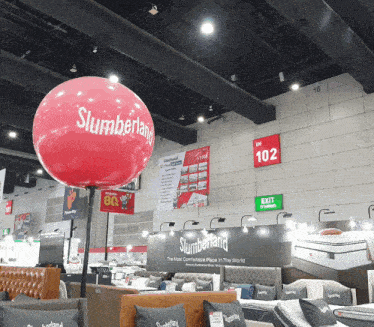 a red slumberland balloon is hanging from the ceiling of a store