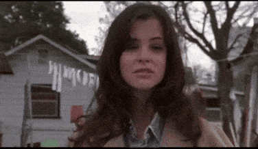 a woman is standing in front of a house with a sign on it that says ' a ' on it .