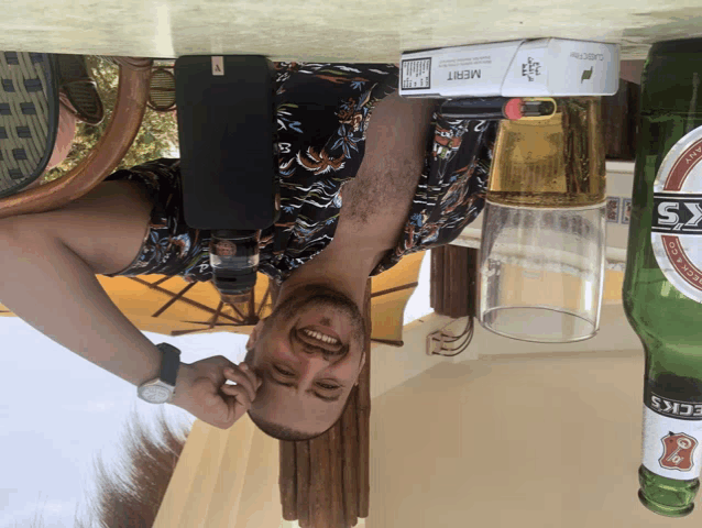 a man is upside down next to a bottle of heineken