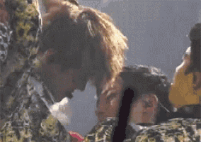 a group of people are standing next to each other on a stage and one of them is holding another person 's head .