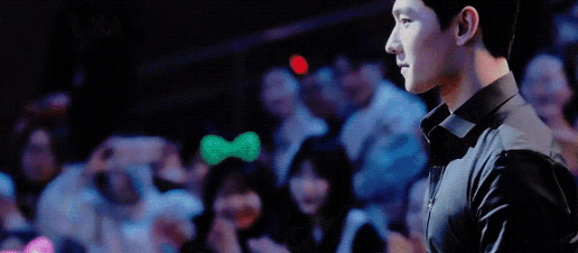 a man in a black shirt is standing in front of a crowd at a concert .