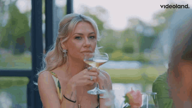 a woman holding a glass of wine with videoland in the corner